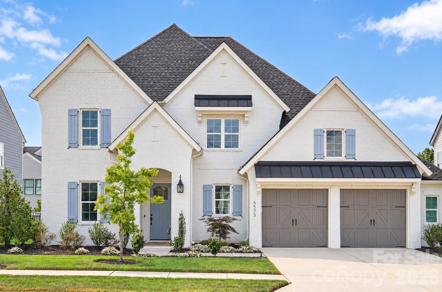 White brick house with blue shutters, a blue front door, and a two-car garage.