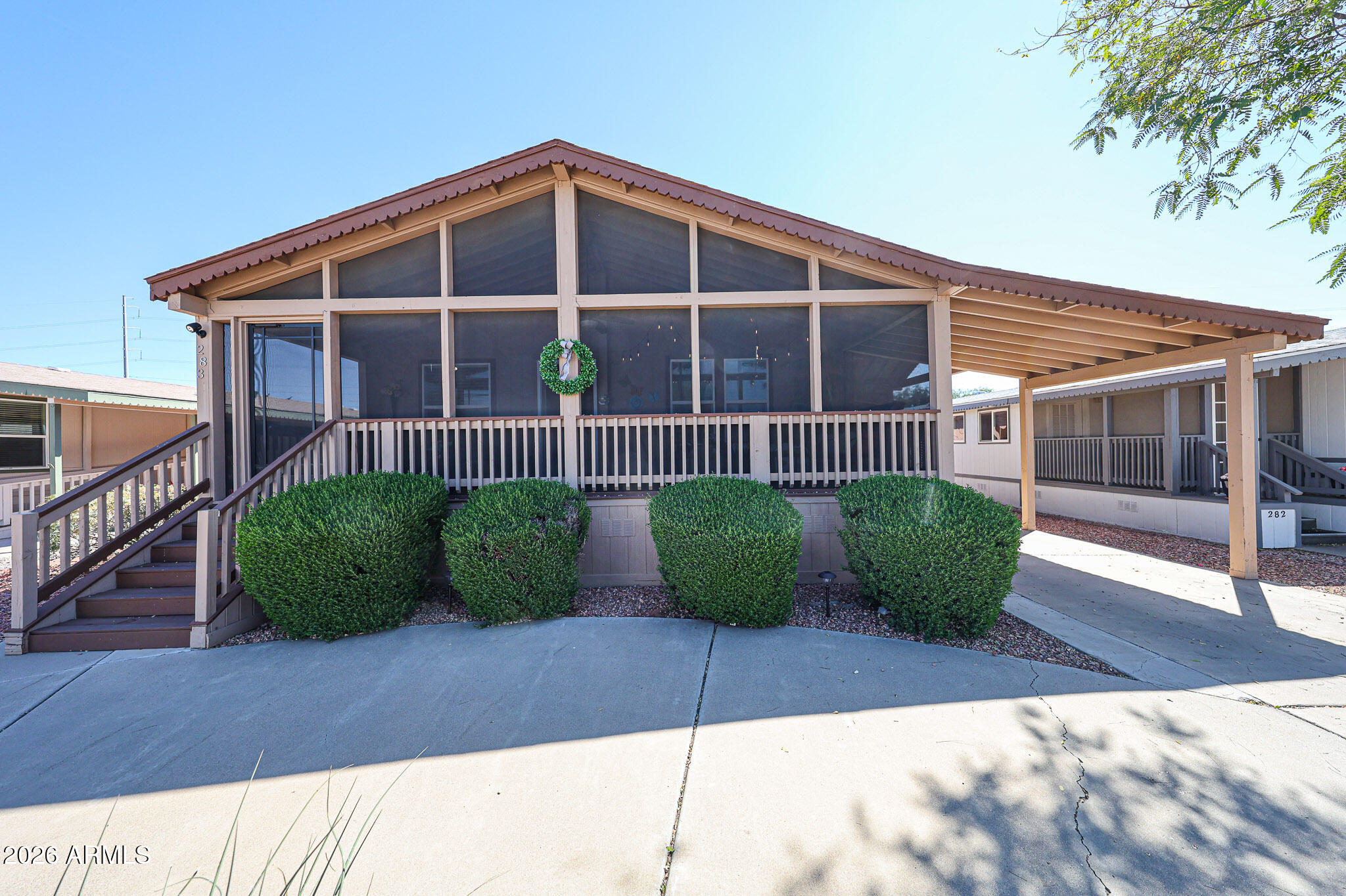 Home with a peaked roof, screened front porch, entry stairs, and neatly trimmed shrubs.