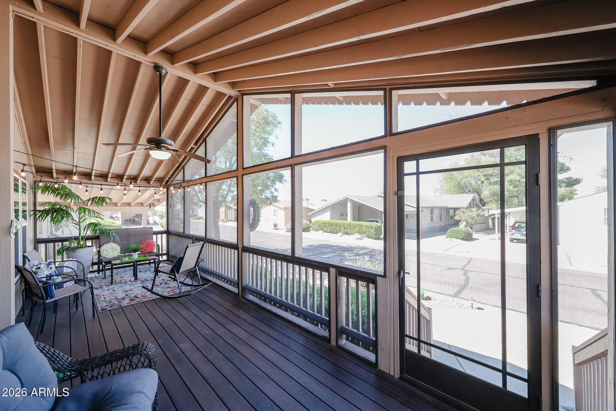 Screened porch with vaulted wood ceiling, large windows, and furnished seating area.