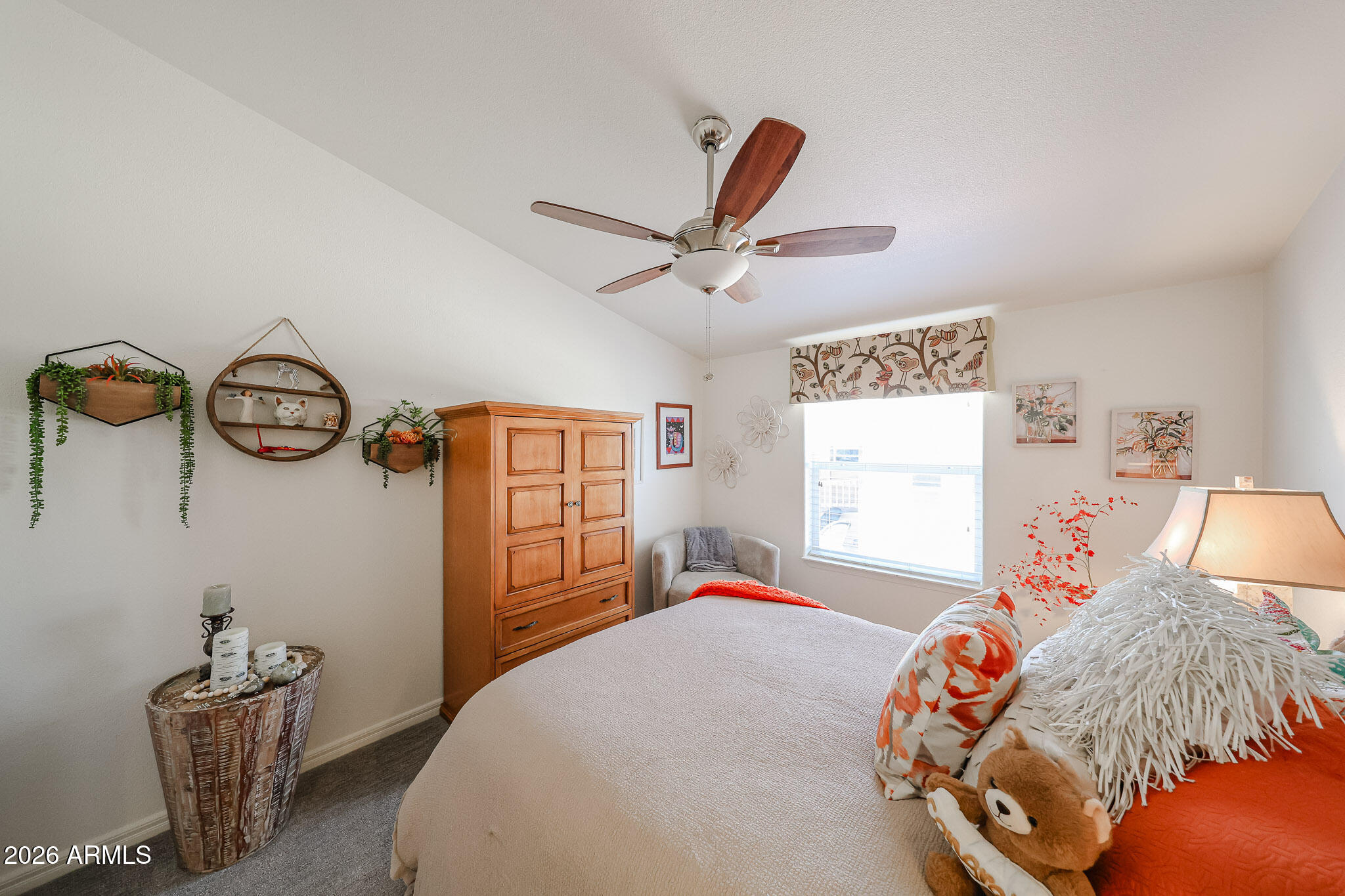 Bedroom with white and orange bedding, a wooden armoire, and a ceiling fan.