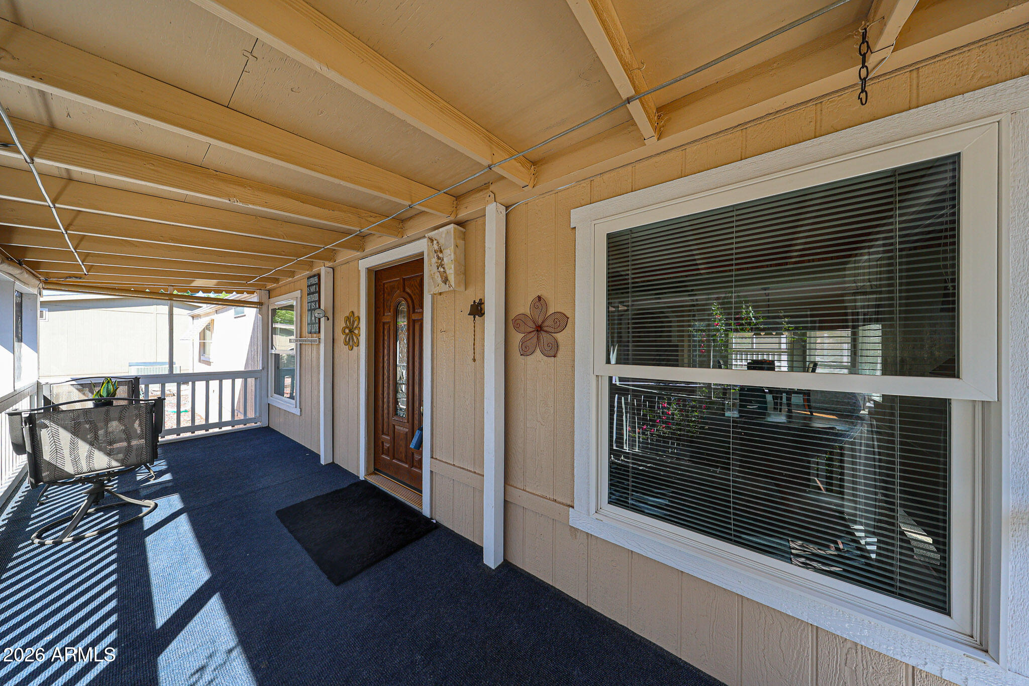 Covered front porch with a wood-beam ceiling, blue floor, and wooden entry door.