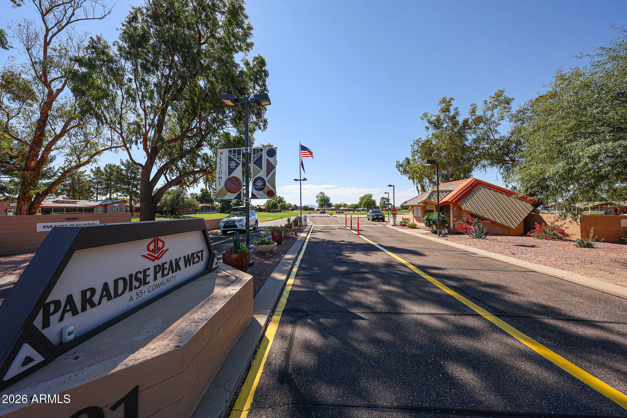 Paradise Peak West community entrance, with a prominent roadside sign and red-roofed guard building.
