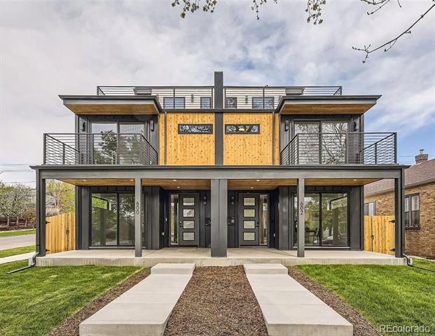 Modern duplex with wood siding, dark framing, upper balconies, and two front entrances.