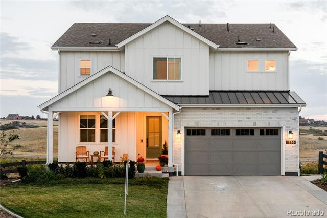 Two-story white house with a covered porch, gray garage, and warm lights glowing at dusk.