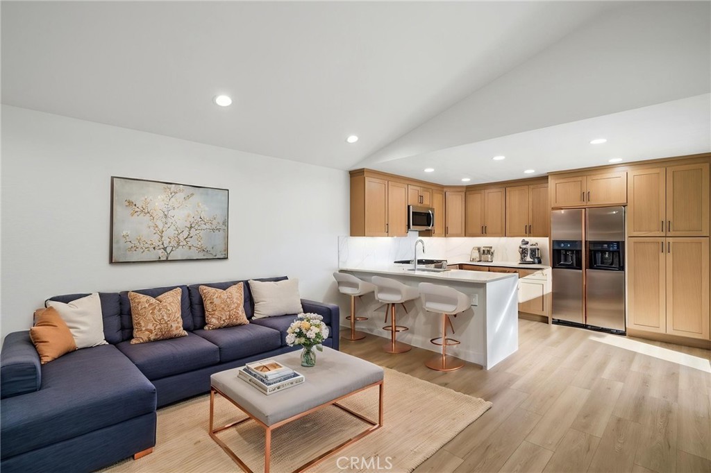 Open-plan living room and kitchen with a navy sectional, light wood cabinets, and a white island.