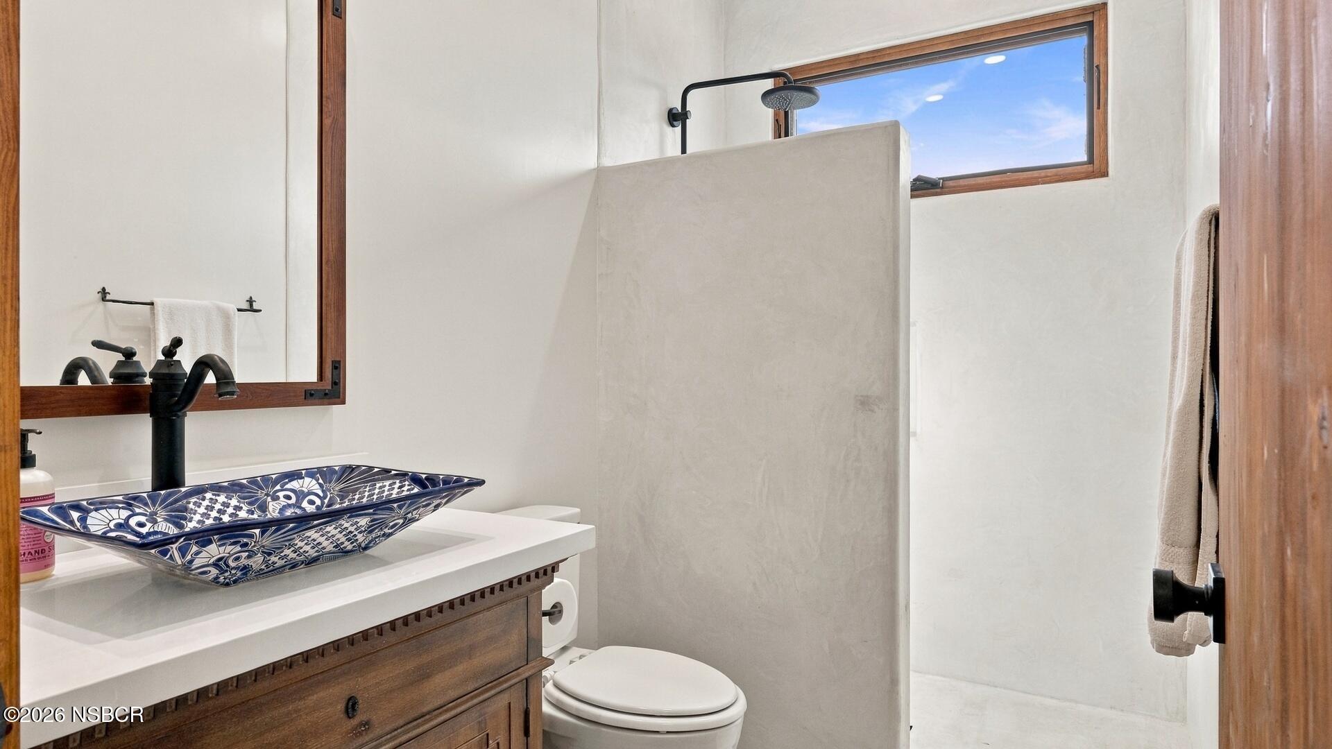 Bathroom with a patterned vessel sink, dark wood vanity, and white walk-in shower.