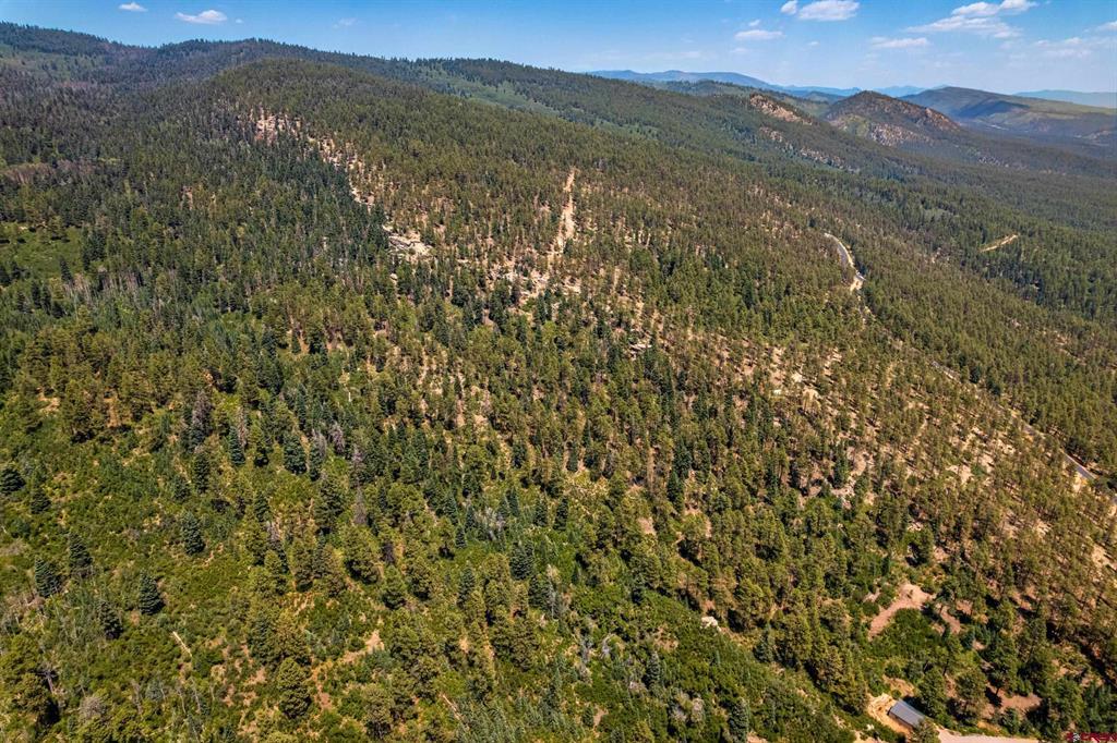 Aerial view of wooded mountain land with scattered clearings and forested ridgelines.
