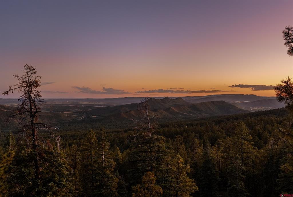 Mountain ridges and forested hills at sunset, viewed across a broad valley.