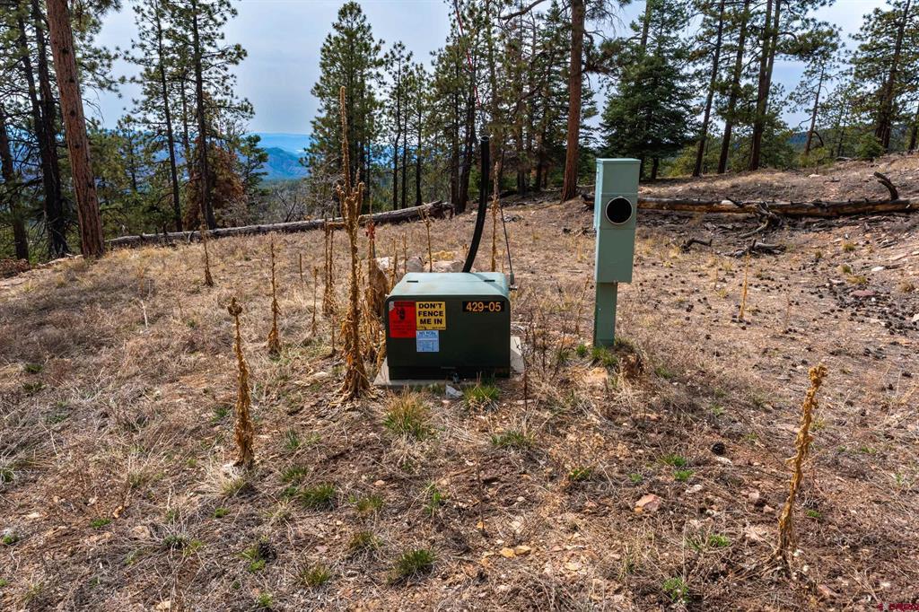 Wooded hillside lot with utility equipment and a distant mountain view.