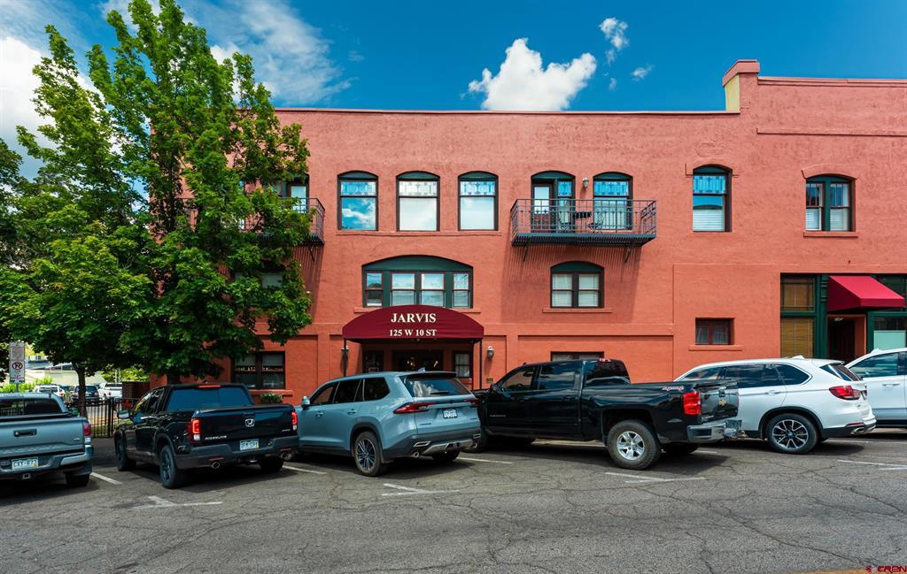 Red commercial building with arched windows and a Jarvis entrance, viewed from the parking lot.
