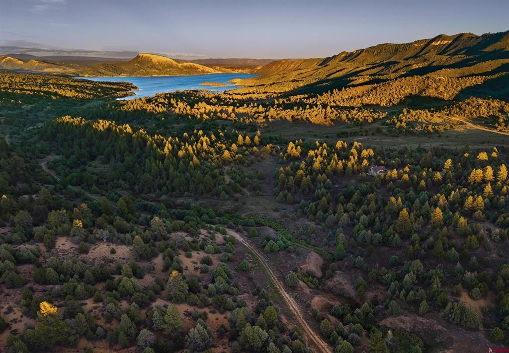Aerial landscape of autumn-colored woodland, a reservoir, and mountain ridges.