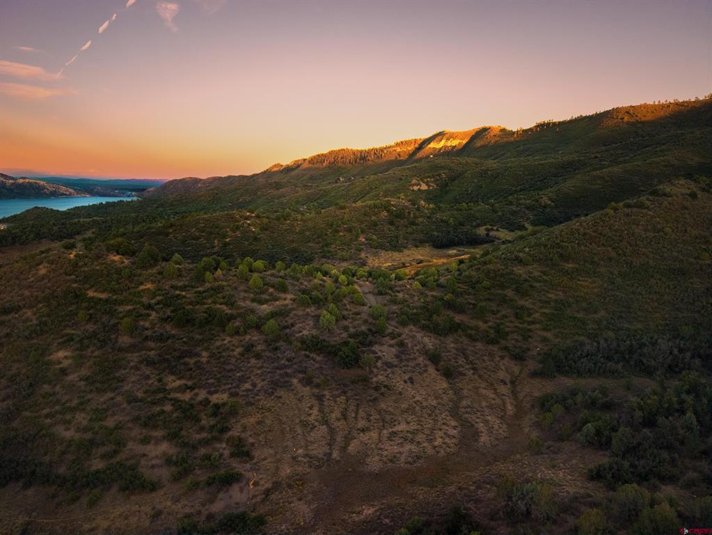 Vacant land with scrub-covered hills, a lake, and a sunset-lit ridgeline.