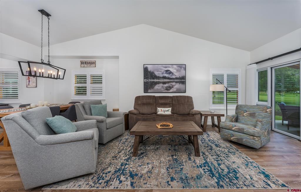 Furnished living room with a brown sofa, blue patterned rug, and sliding glass doors to the lawn.