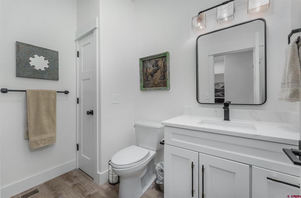Bathroom with white vanity, black-framed mirror, toilet, and western-themed wall art.