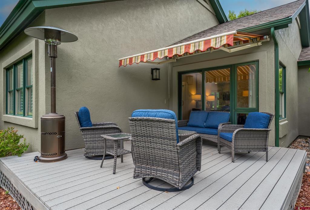 Deck patio with blue-cushioned wicker seating, striped awning, and freestanding heater.