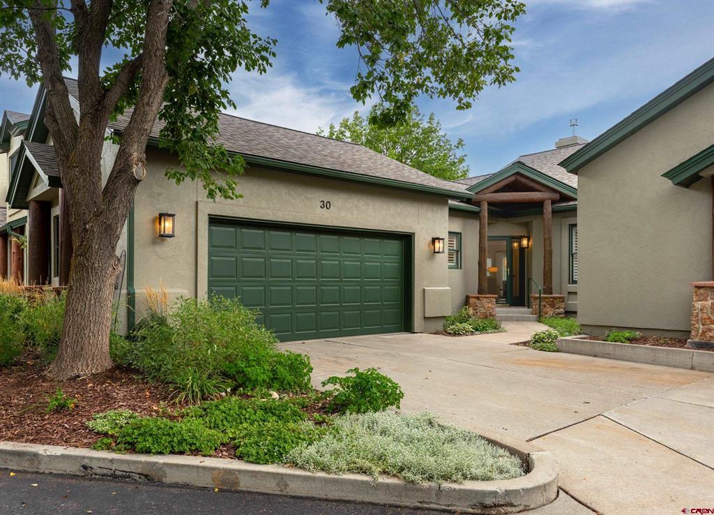 Home exterior with a dark green double garage door, covered entry, and landscaped garden.