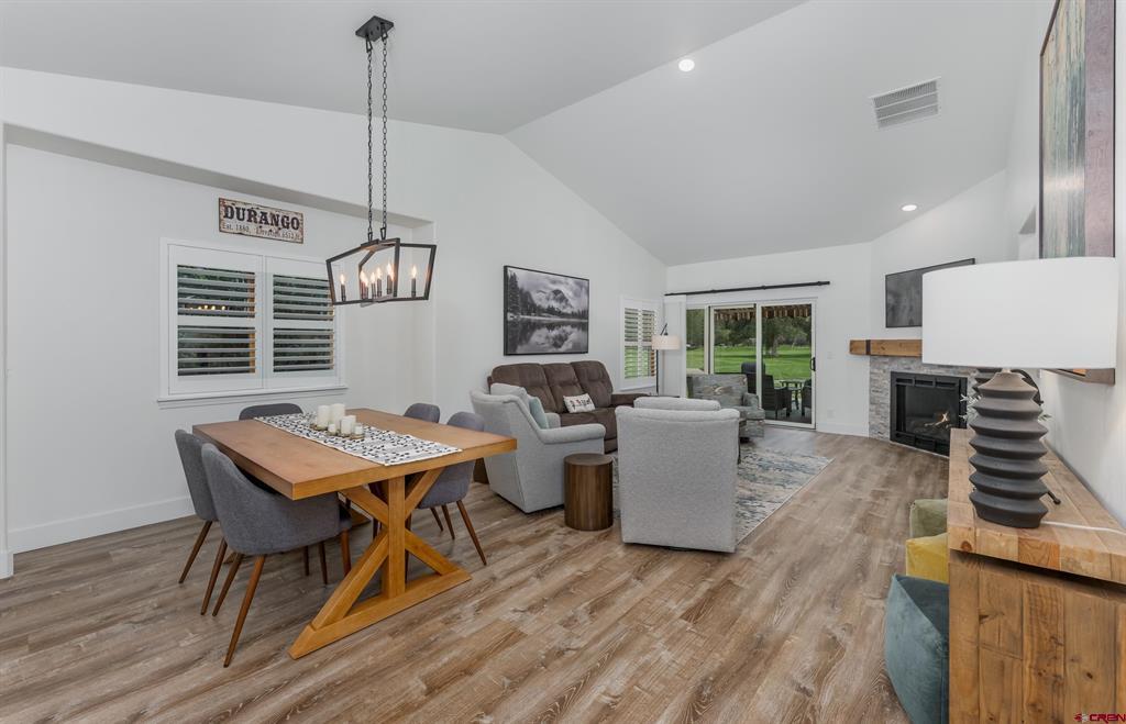 Open-plan living and dining room with gray seating, a fireplace, and sliding doors to a lawn.