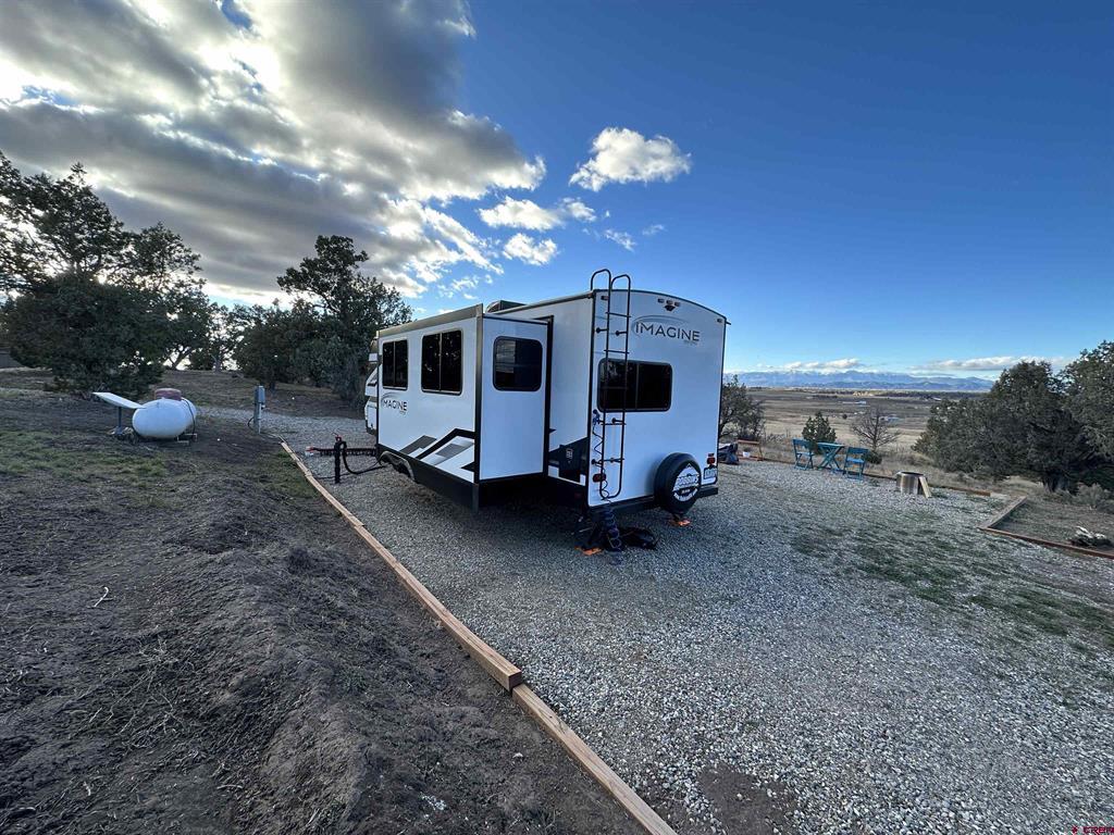 Imagine travel trailer on a gravel pad overlooking open fields and distant mountains.
