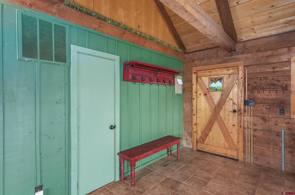 Rustic entryway with green paneled walls, a red bench and coat hooks, and a wooden barn door.