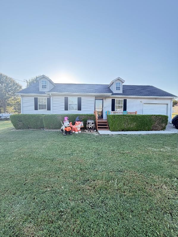 White single-story house with two dormers, an attached garage, and Halloween decorations by the front porch.