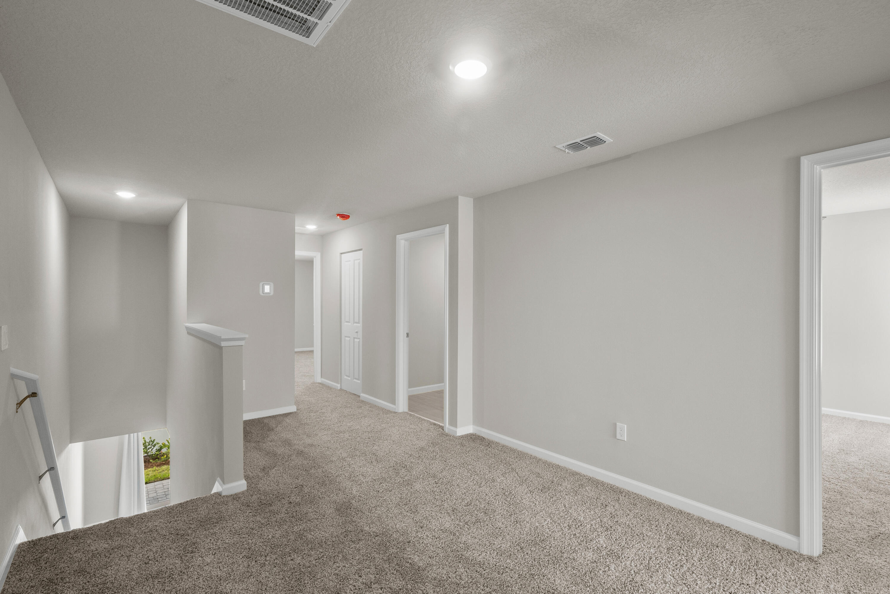 Carpeted upper-floor landing with several doorways and an open stairwell.