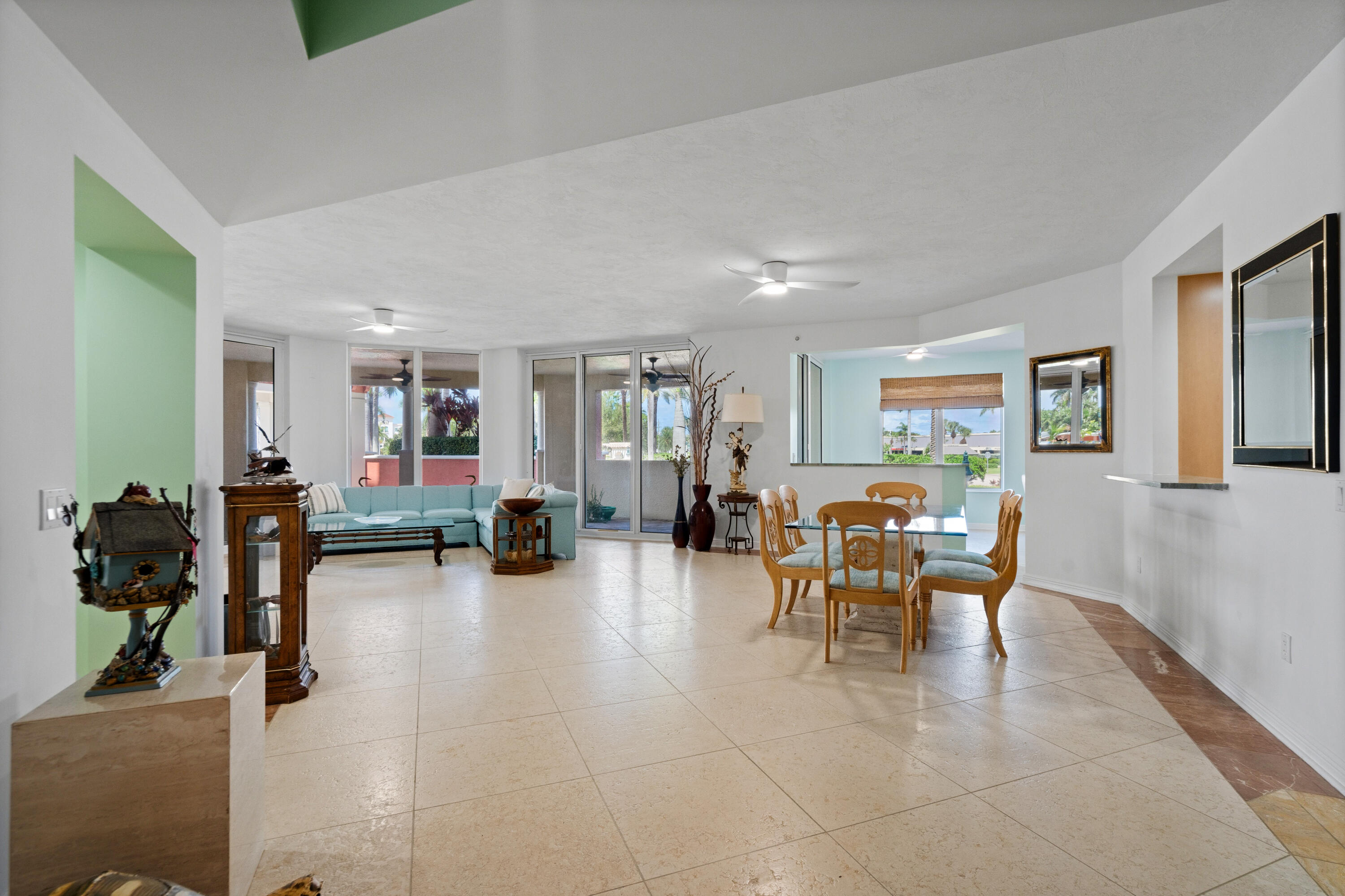 Open-plan living and dining room with a light blue sectional, wooden dining set, and sliding glass doors.