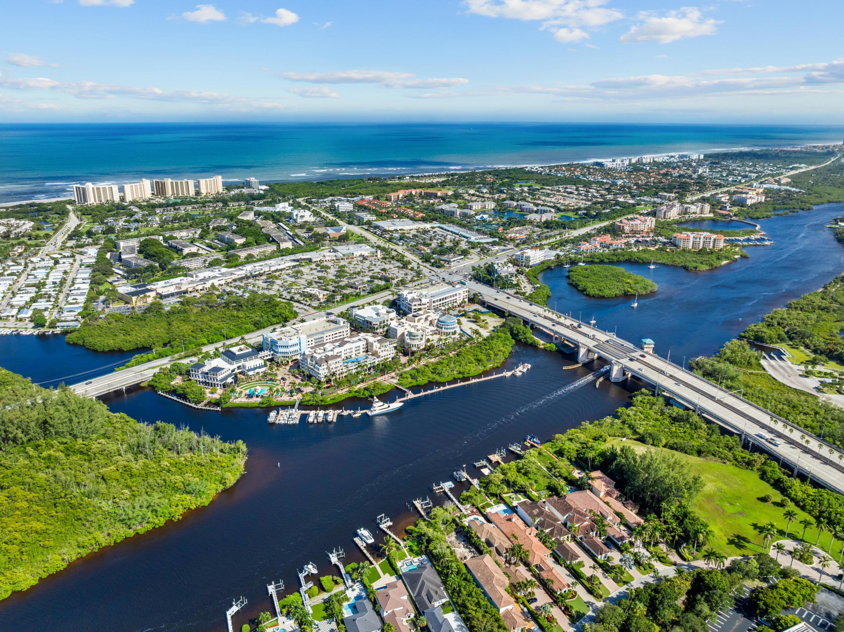 Aerial view of Jupiter’s inlet and coastline, with a bridge, marinas, and the Atlantic Ocean.