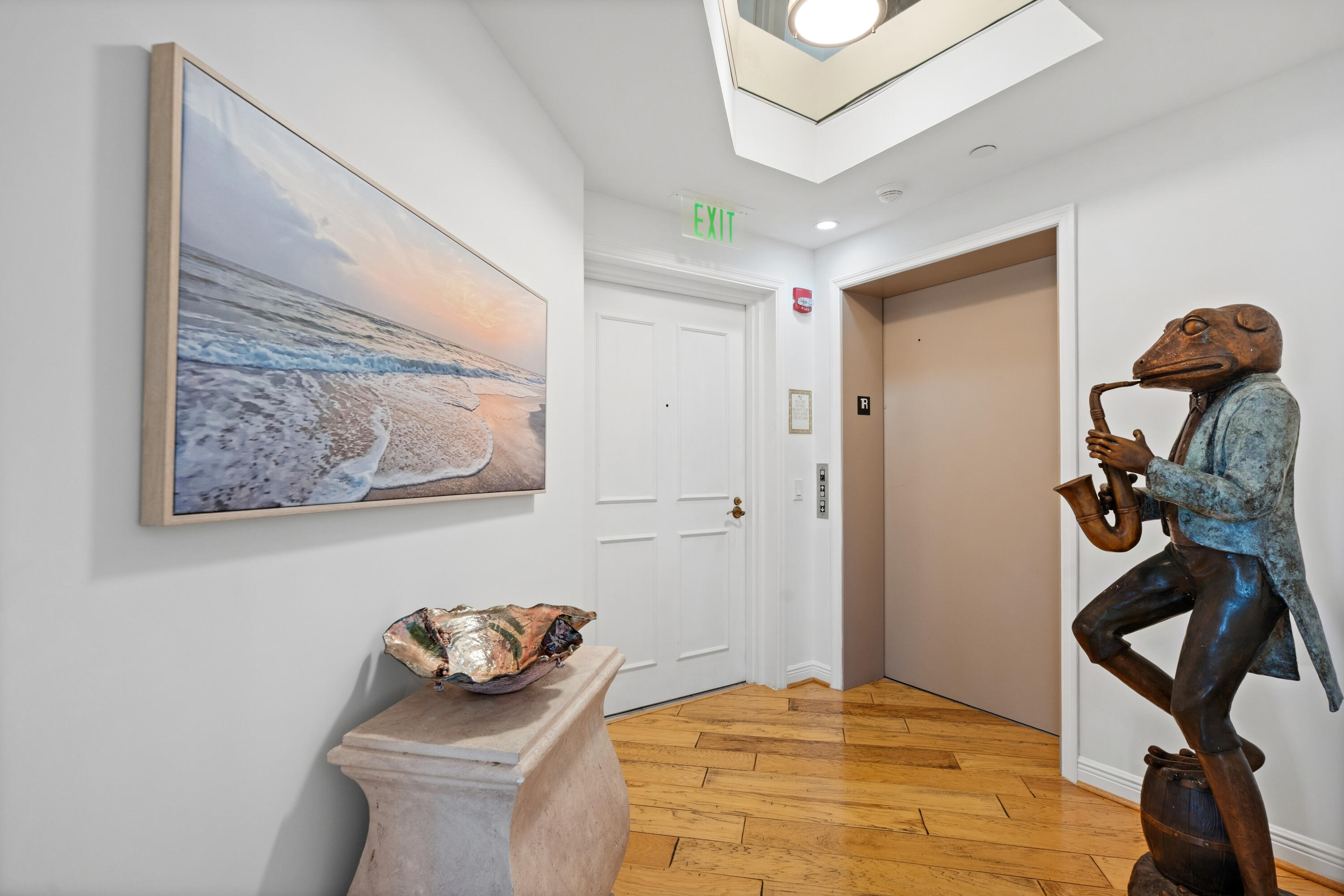 Elevator lobby with wood flooring, beach artwork, and a large sculpture of a musician.