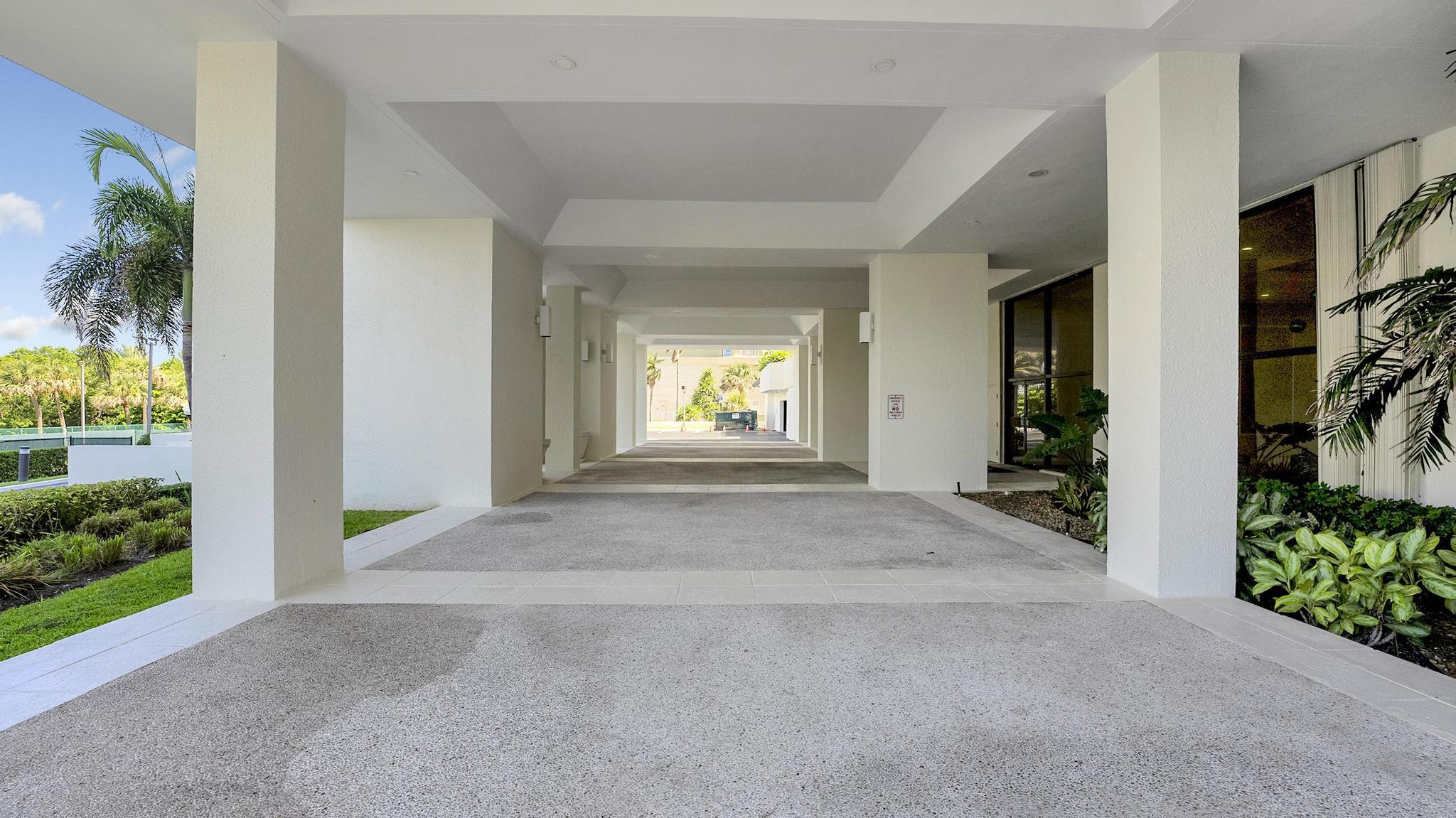 Condominium porte-cochère with white columns, a paved drive and tropical landscaping.
