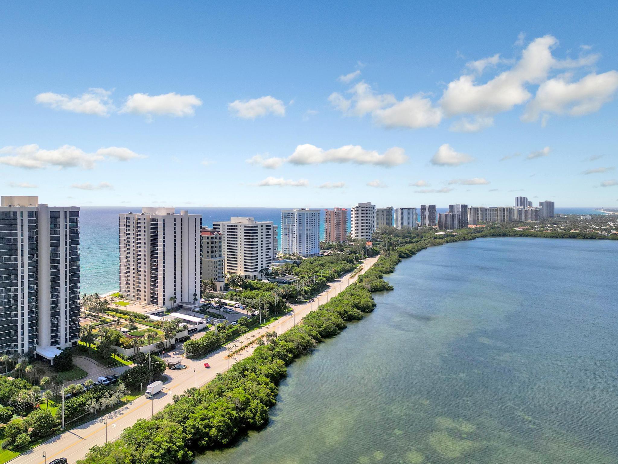 Aerial view of coastal condominiums between the ocean and a broad, calm waterway.