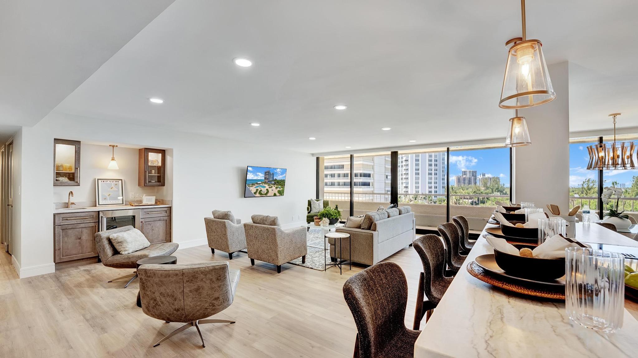 Open-plan living and dining room with floor-to-ceiling windows overlooking high-rise buildings.