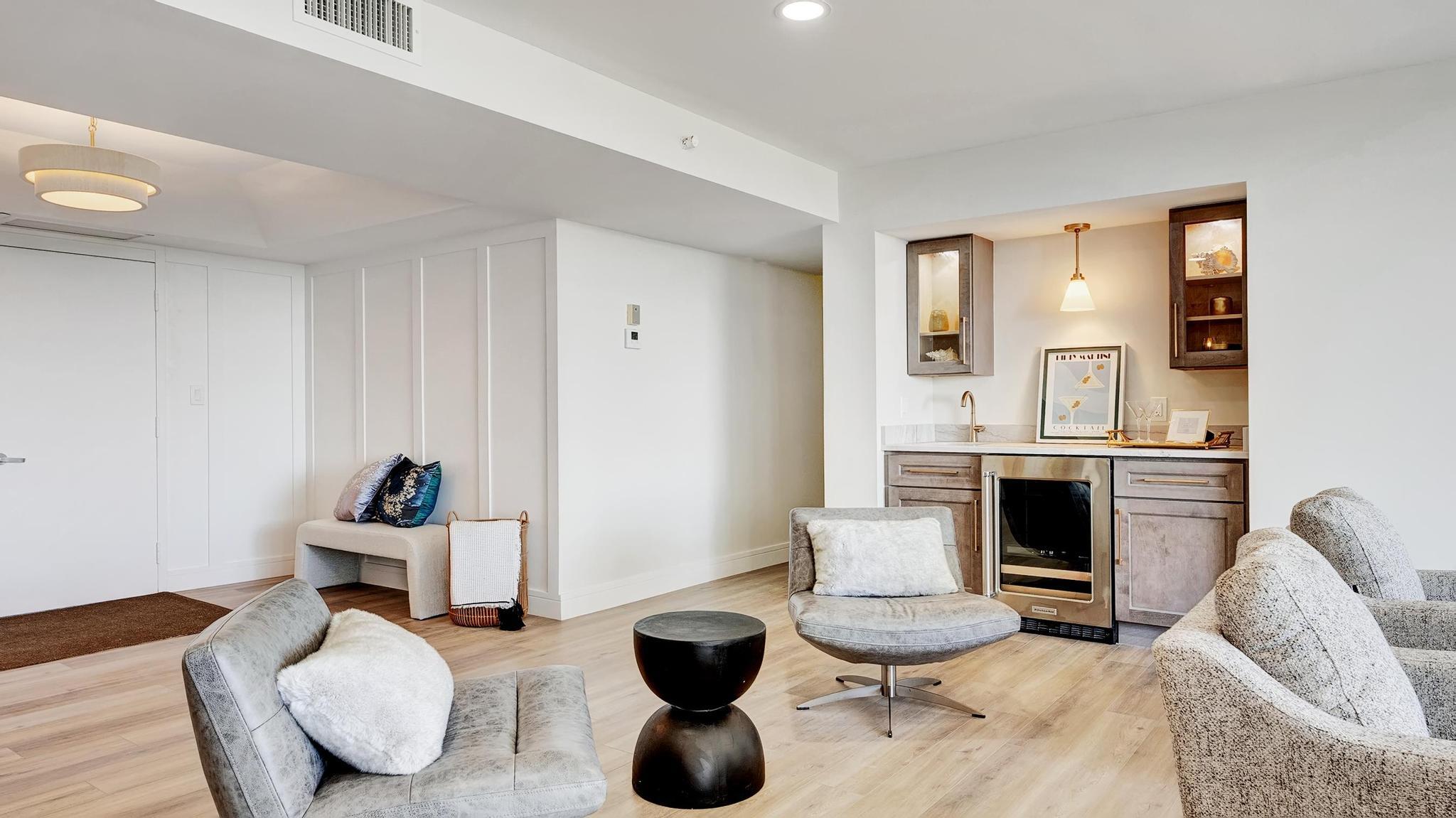 Furnished living room with gray lounge chairs and a built-in wet bar.