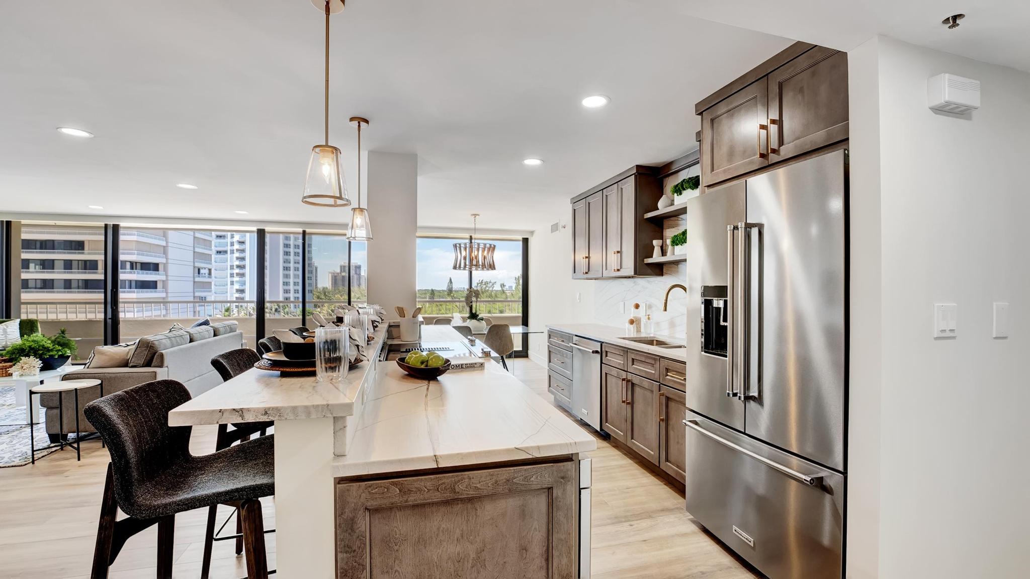 Open-plan condo kitchen with a marble island, dark wood cabinets, and high-rise views through expansive windows.