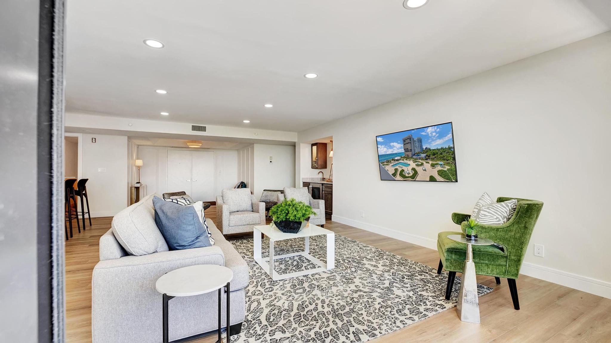 Furnished living room with white sofas, a green accent chair, and a large patterned rug.