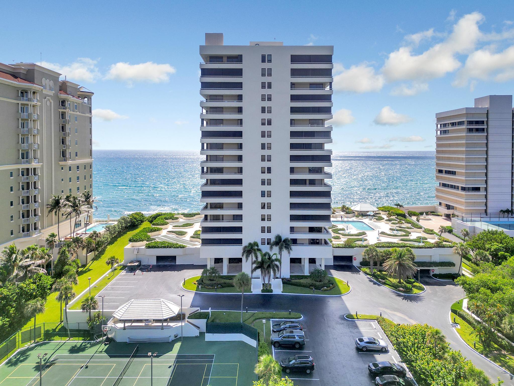 Oceanfront condominium tower with a pool, tennis courts, and landscaped grounds.