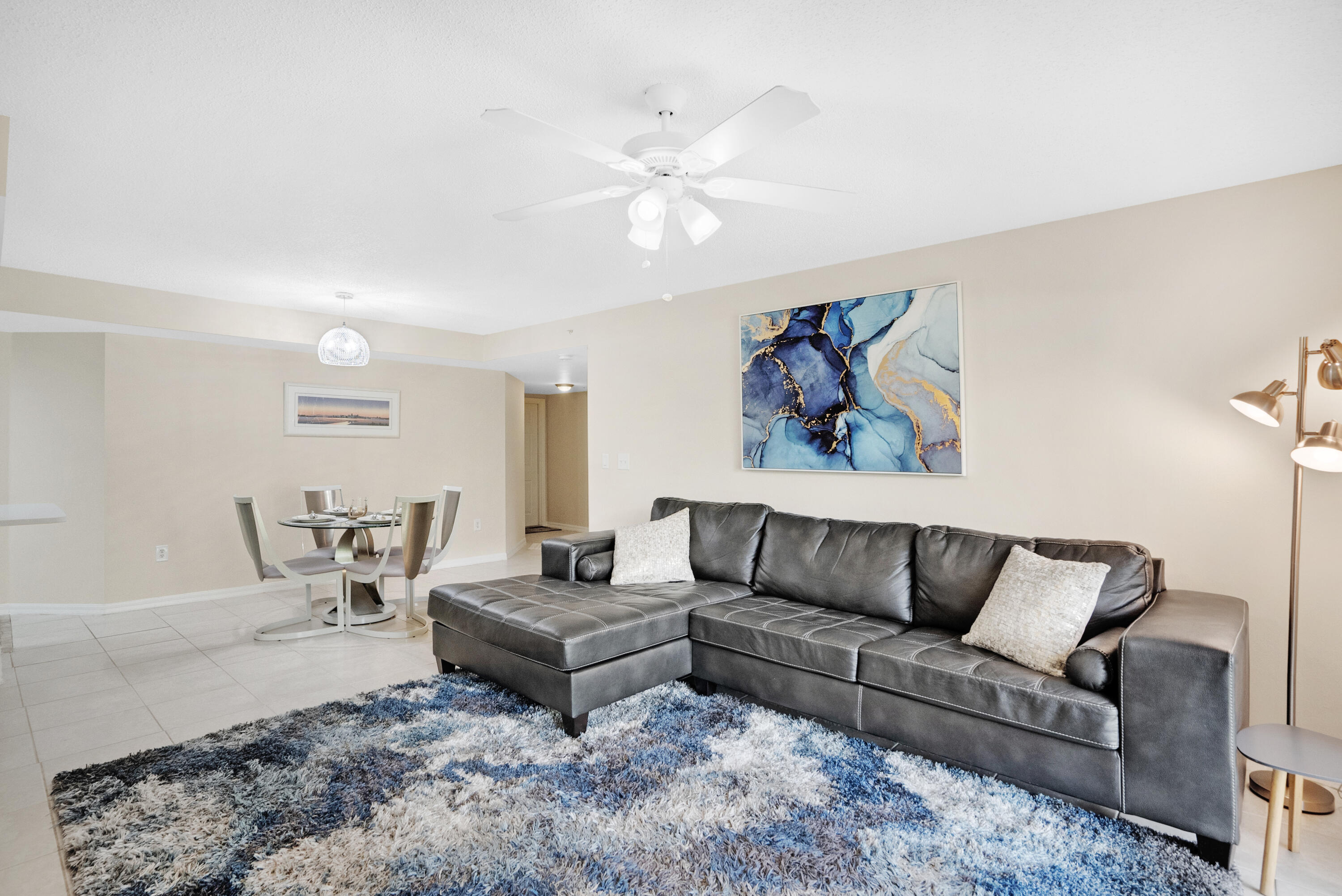 Living room with a dark gray sectional, blue-and-white rug, and adjacent round dining table.