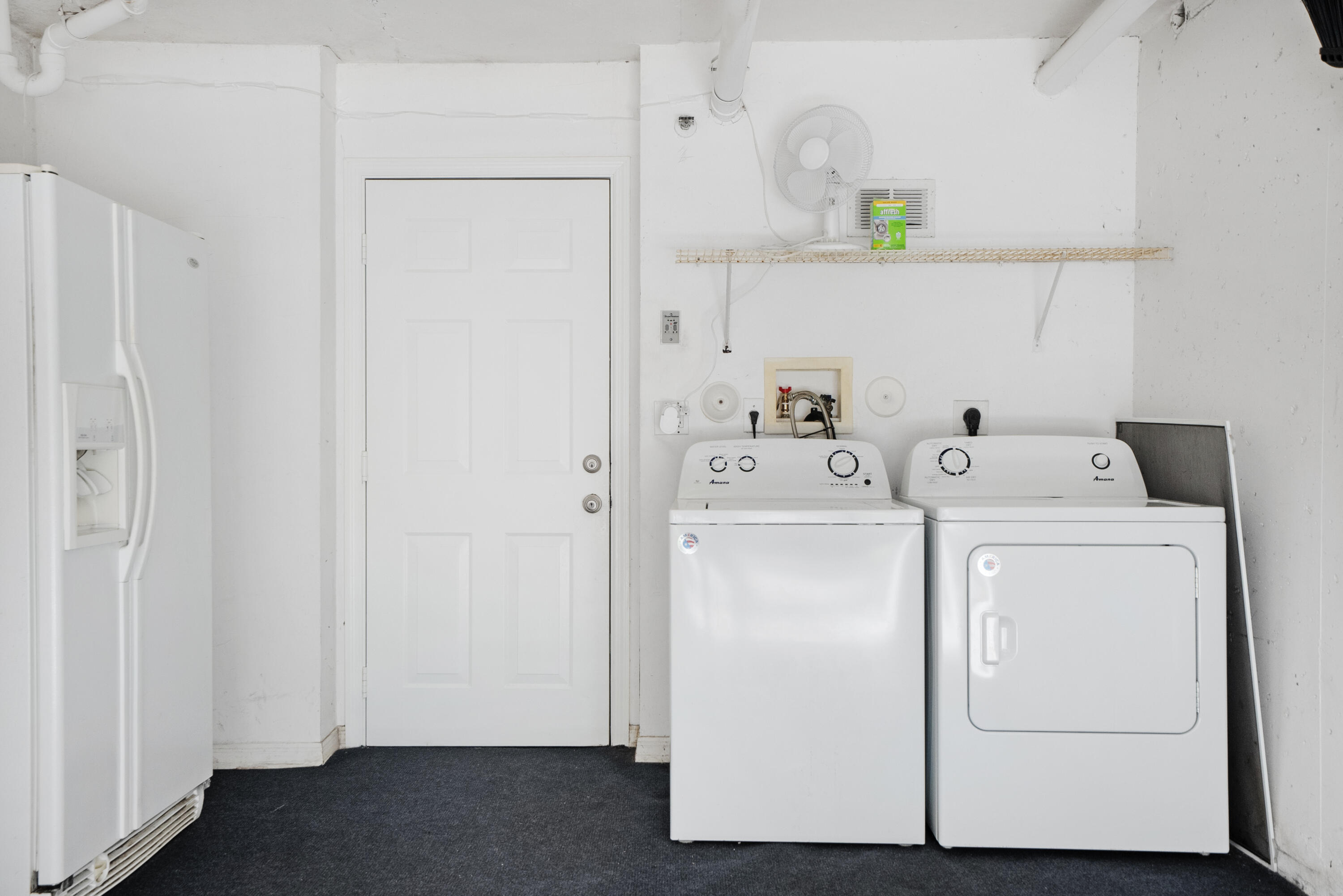 Laundry room with a white washer and dryer beside a refrigerator.