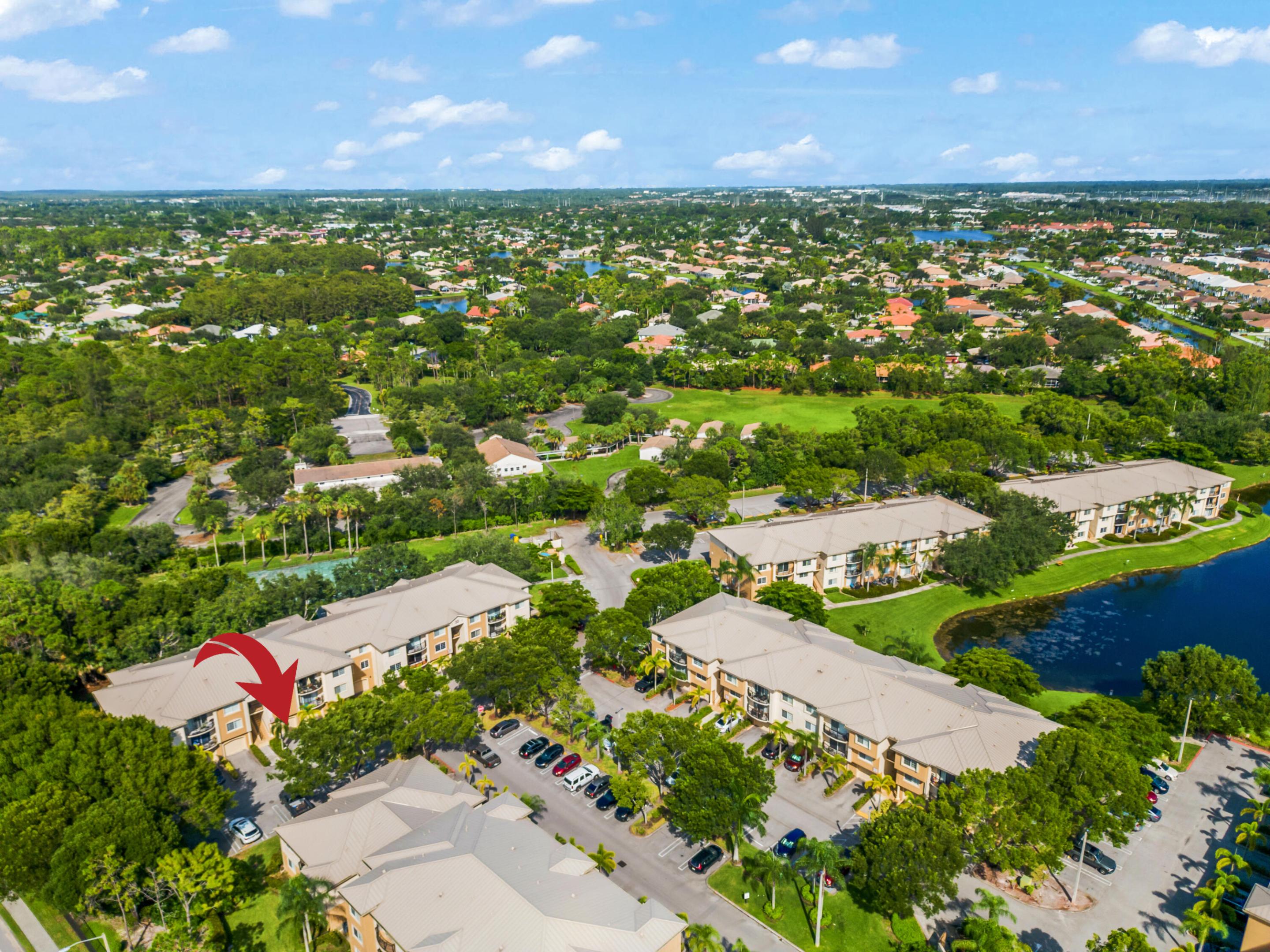 Aerial view of a condo complex, with a red arrow marking one building beside a pond.