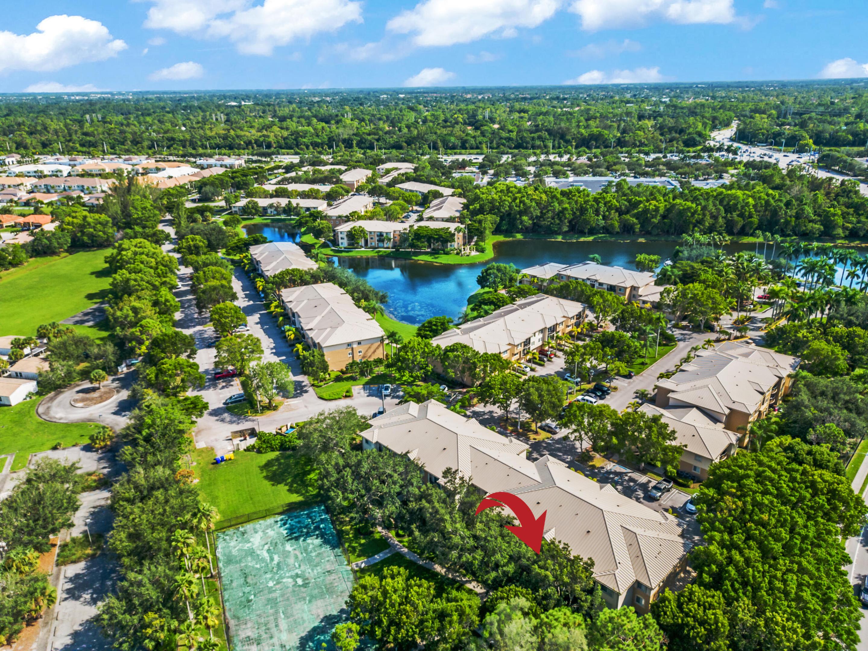 Aerial view of condominium buildings beside a lake, with a red arrow marking one building.