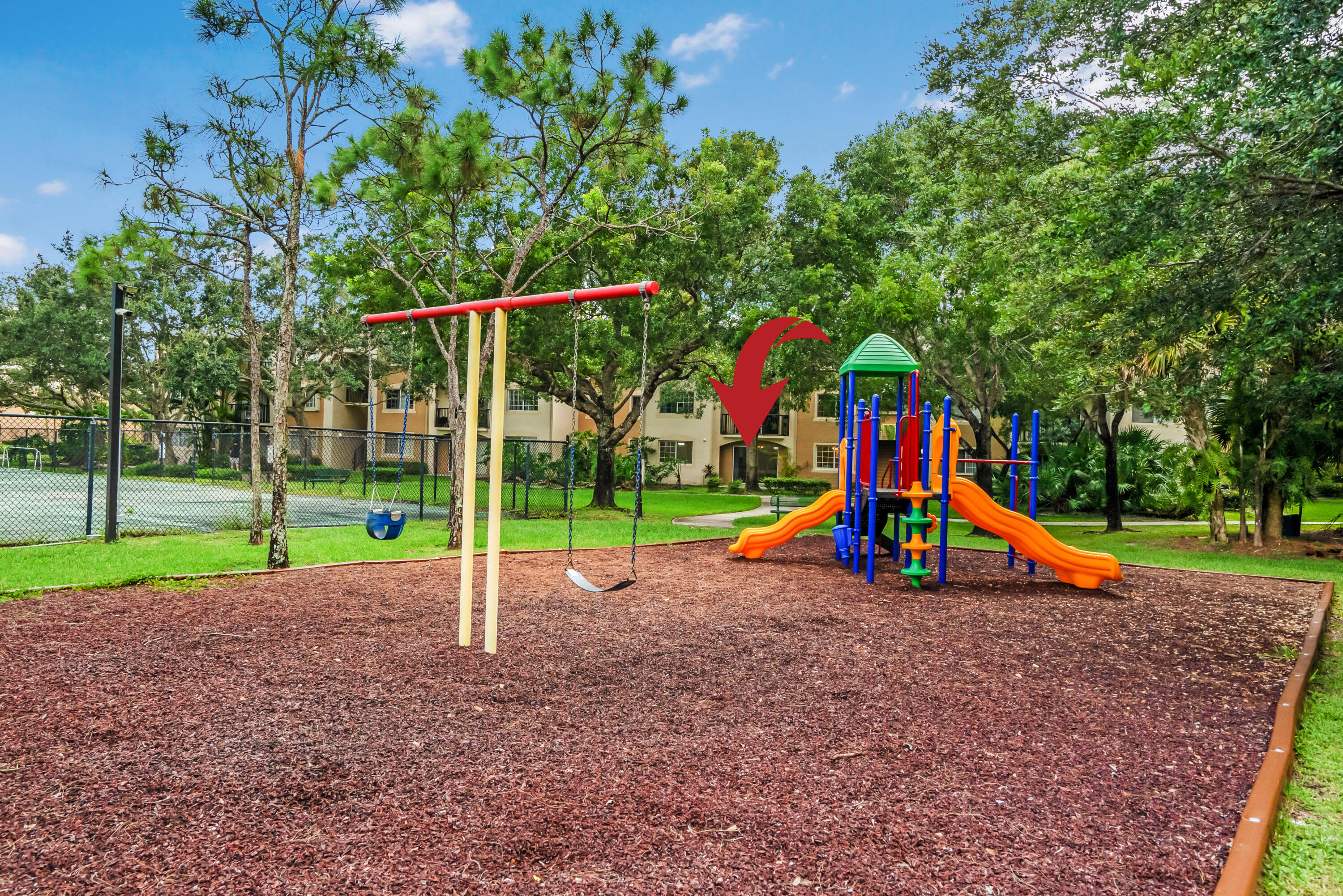 Apartment community playground with colorful slides and swings; a red arrow points toward the building.