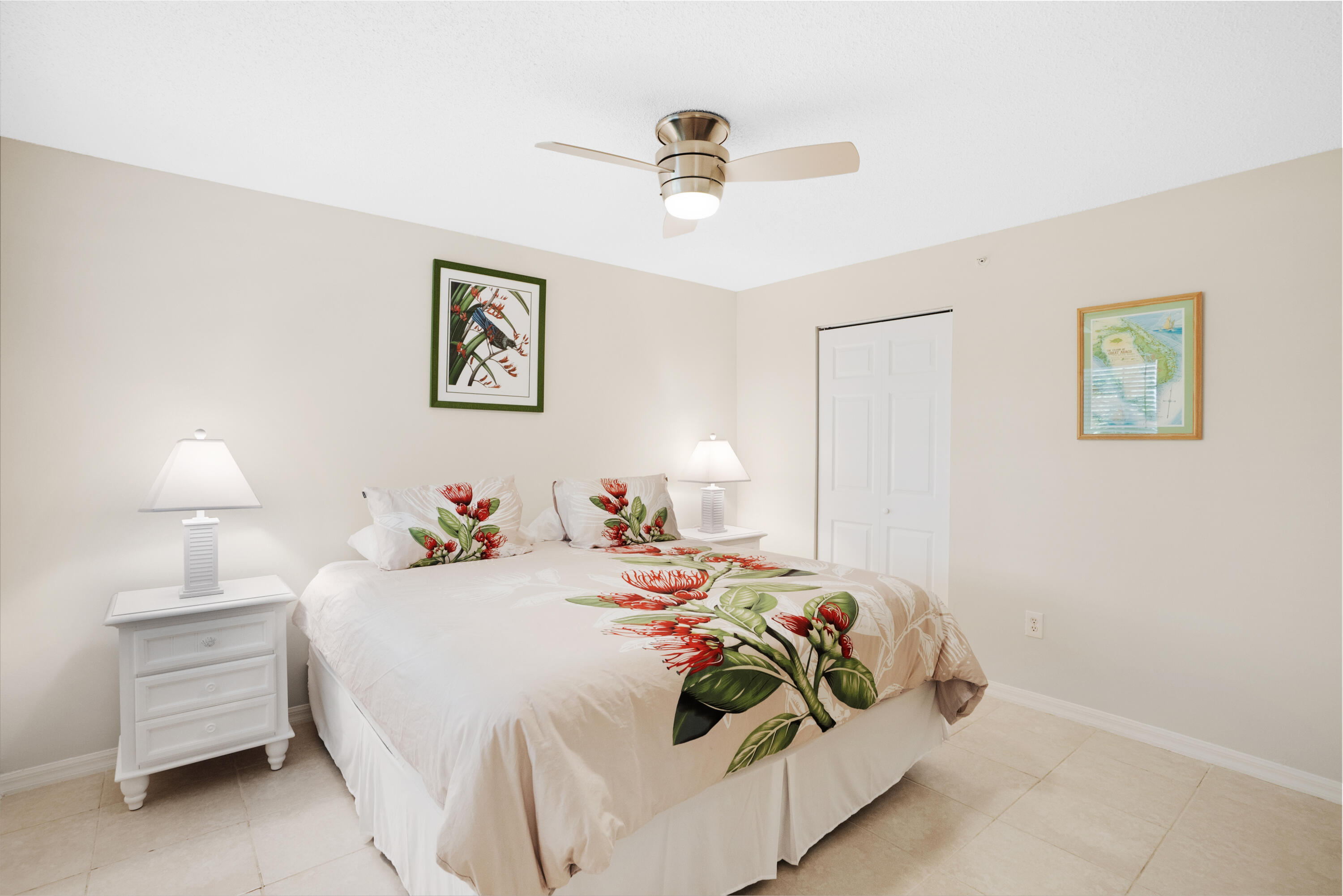 Bedroom with red floral bedding, matching bedside lamps, and a ceiling fan.