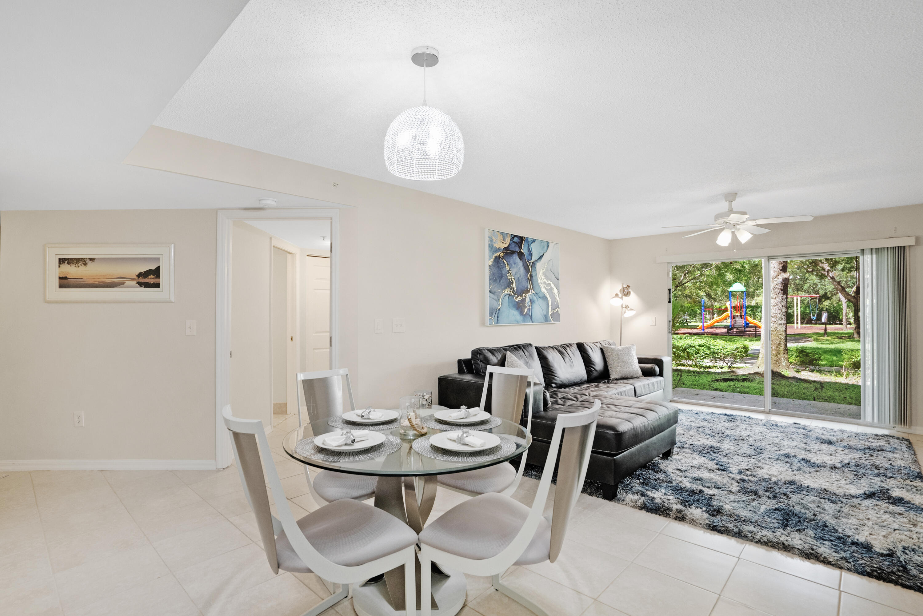 Furnished living and dining area with a dark sectional sofa and sliding doors overlooking a playground.