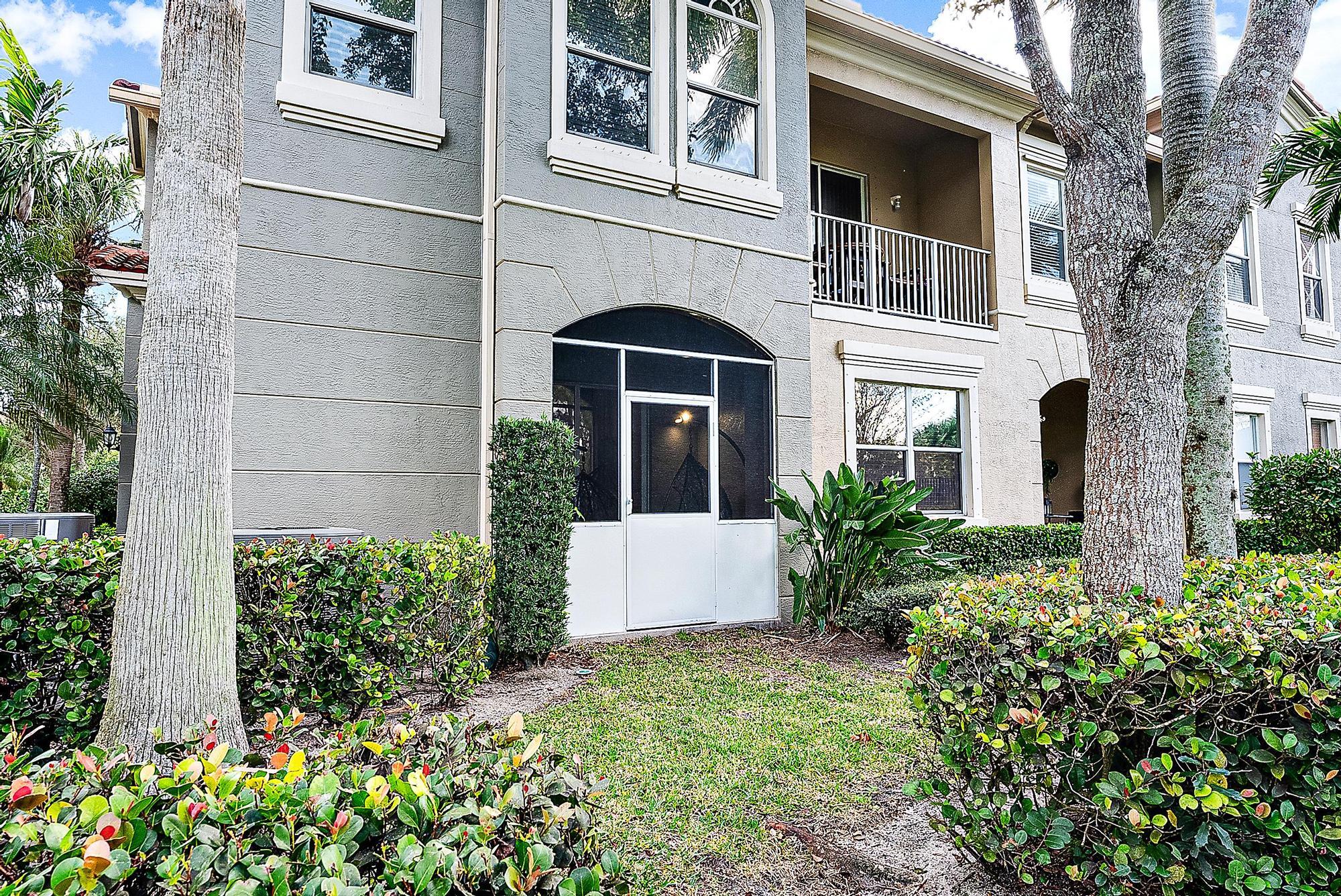Two-story residence with a screened patio, upper balcony, and mature trees framing the landscaped yard.