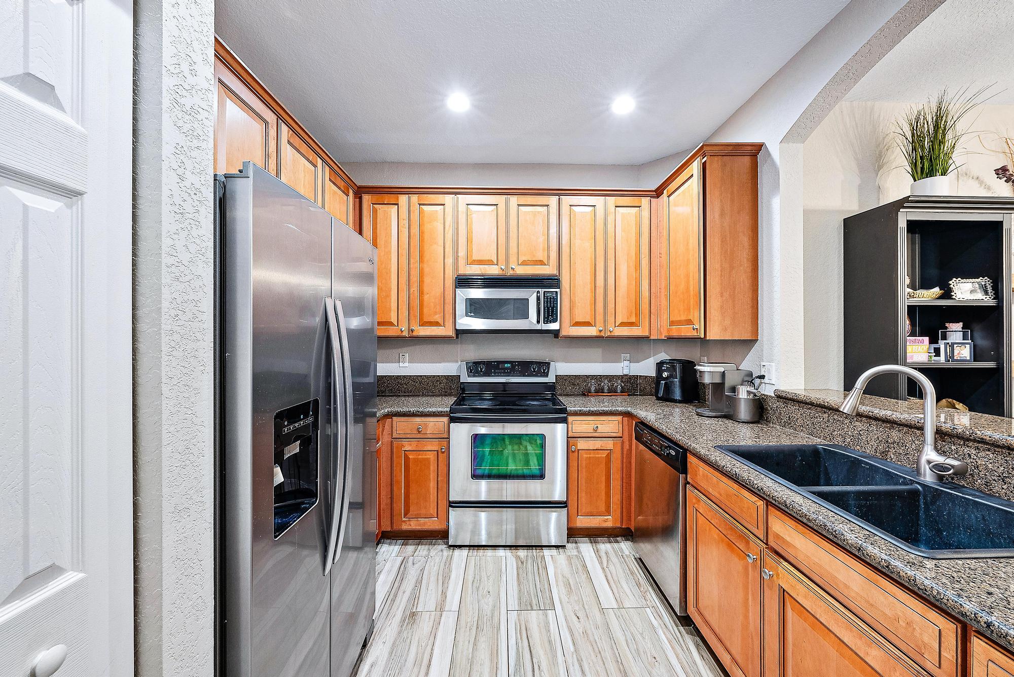 Kitchen with warm wood cabinets, stainless steel appliances, and a large dark sink.