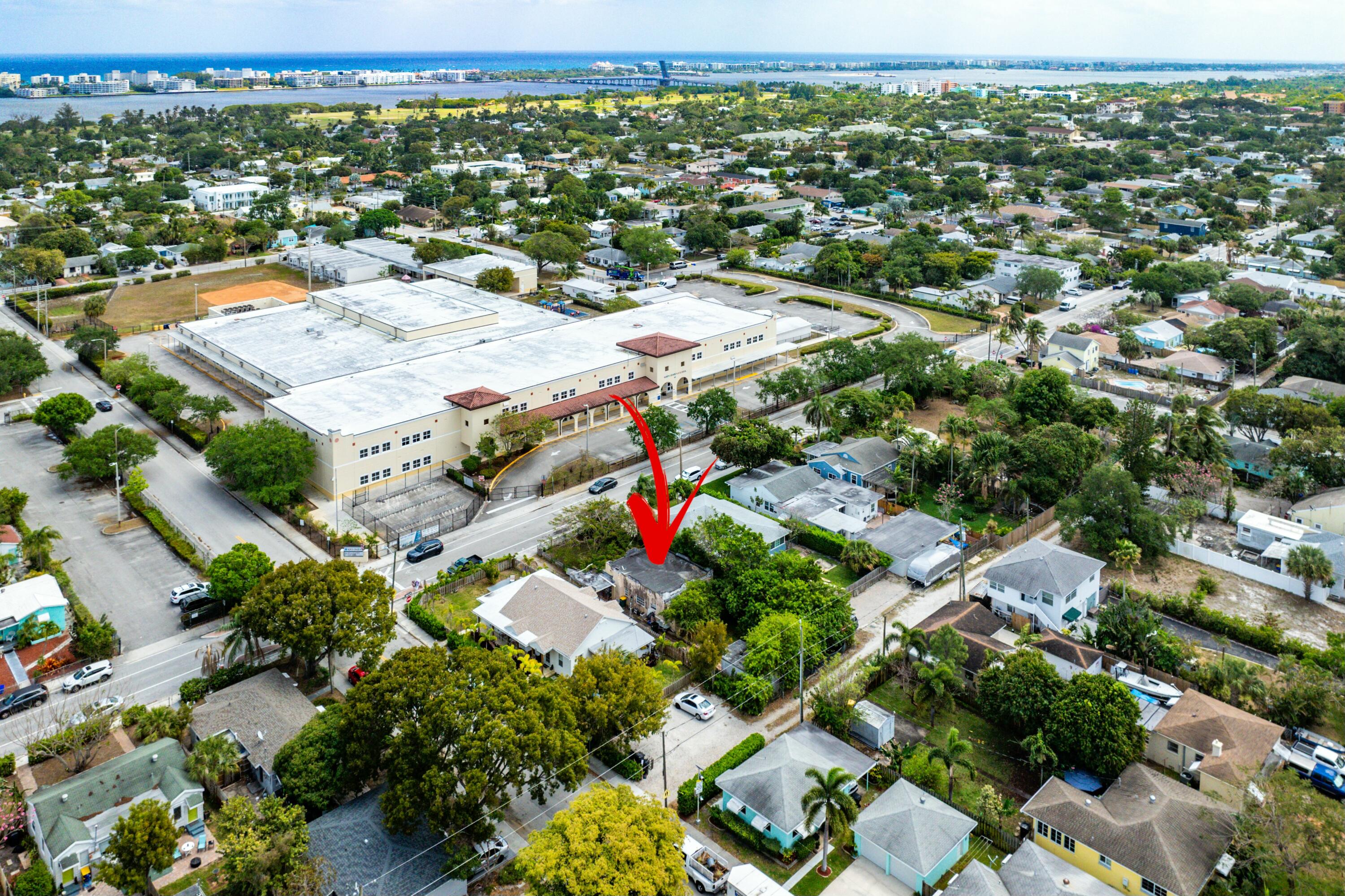Aerial view of a Lake Worth Beach home marked by a red arrow, with the coastline in the distance.