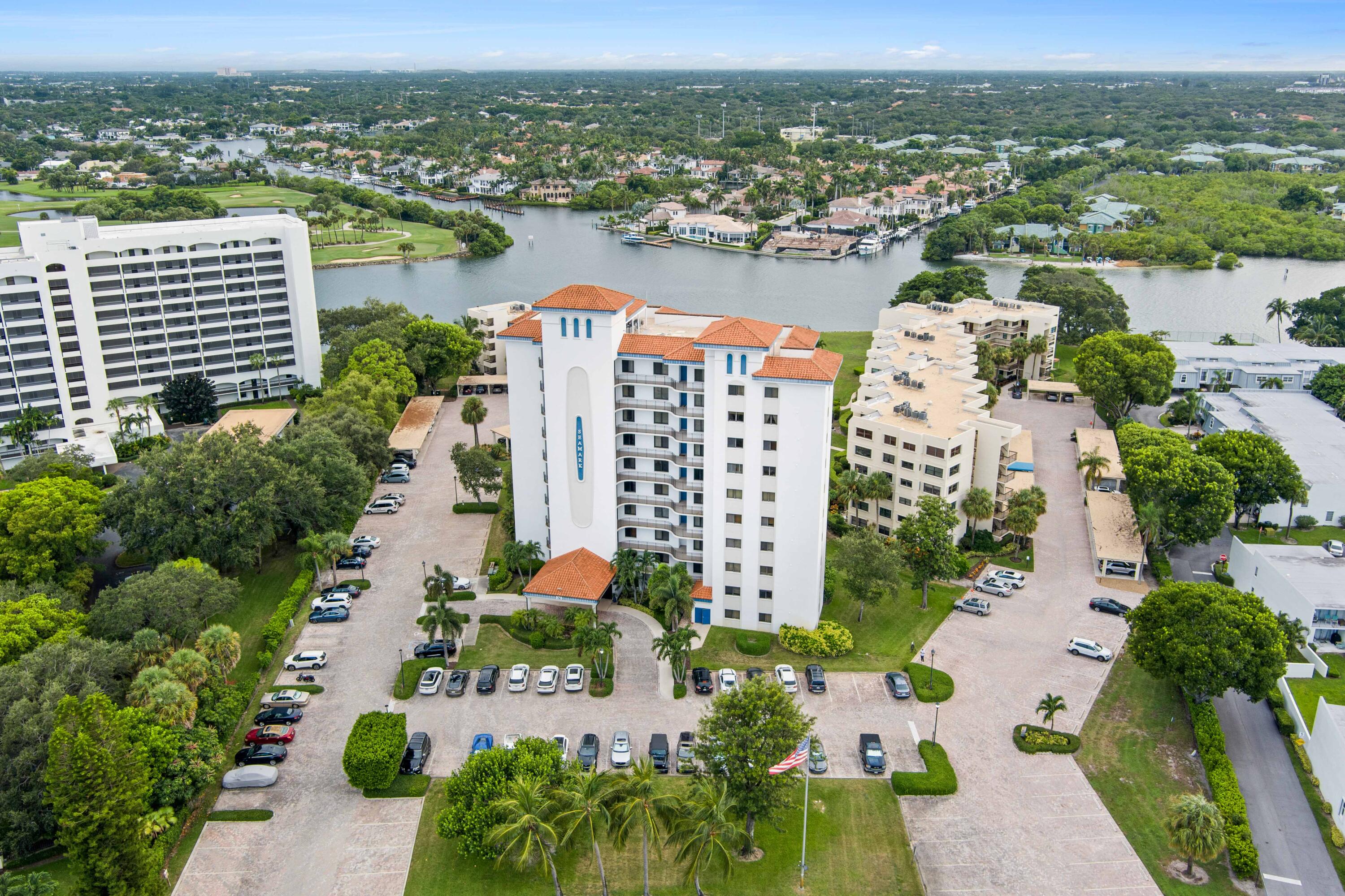 Seawalk condominium beside a waterway, with waterfront homes and a golf course in the distance.