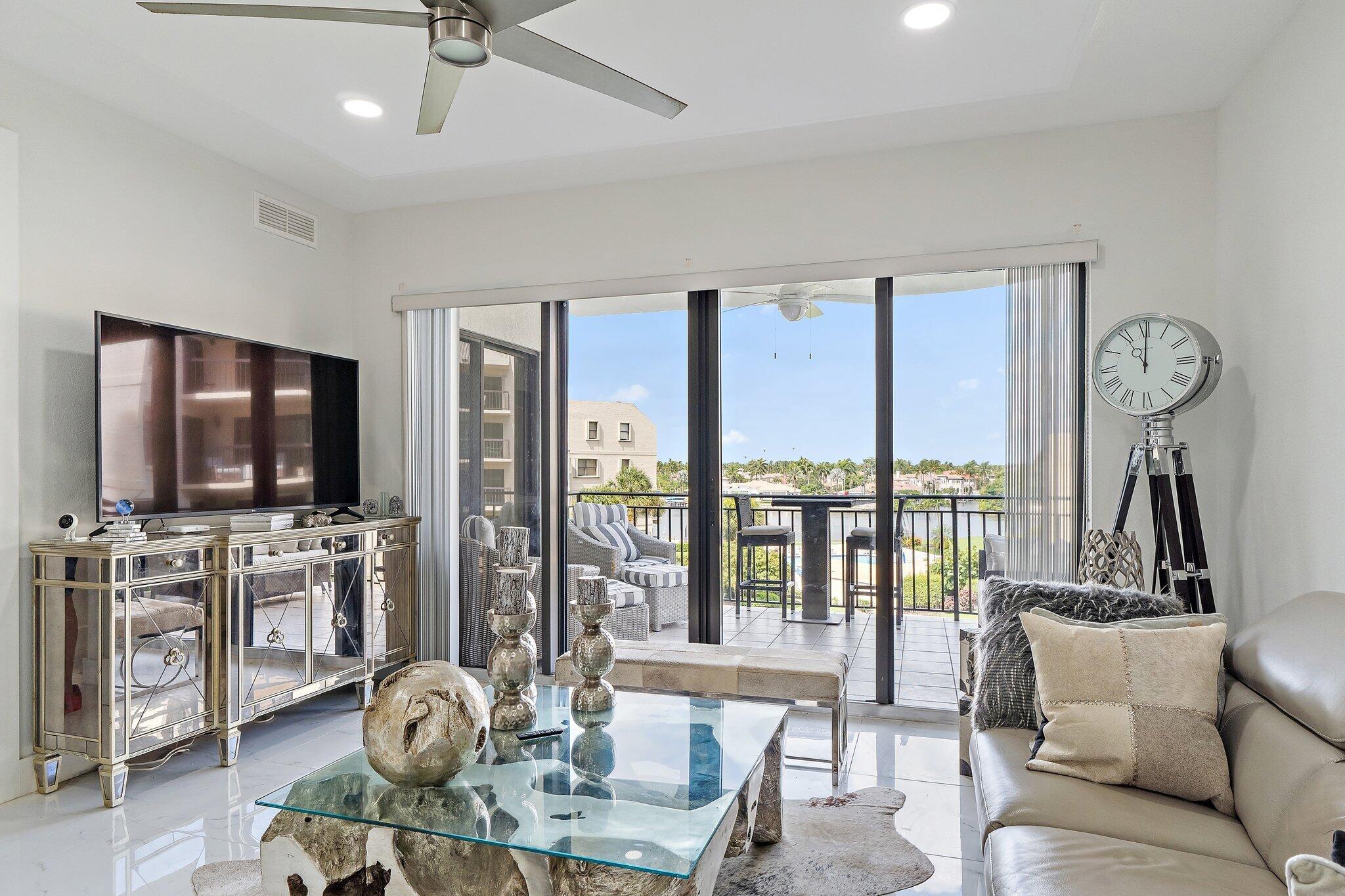 Living room with sliding doors to a balcony overlooking the water and palm-lined homes.