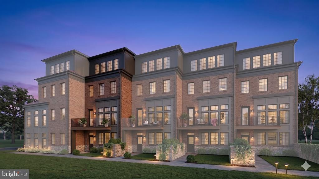Row of brick townhomes with balconies and illuminated windows at dusk.