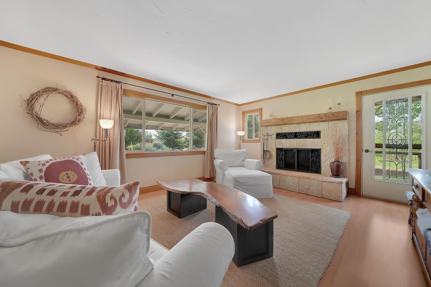 Living room with a stone fireplace, large windows, and live-edge coffee tables.