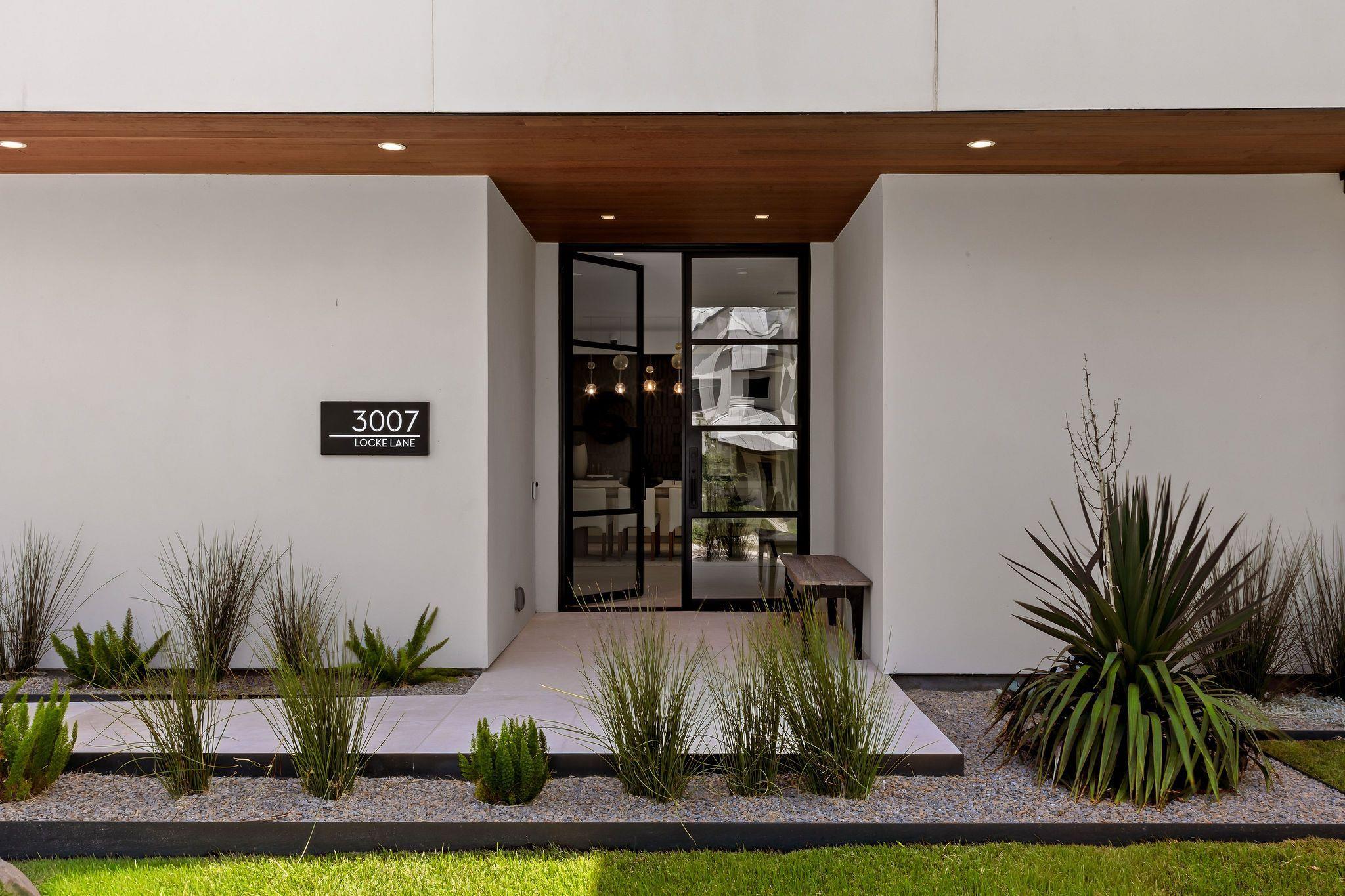 Modern home entrance with black-framed glass doors and landscaped beds at 3007 Locke Lane.